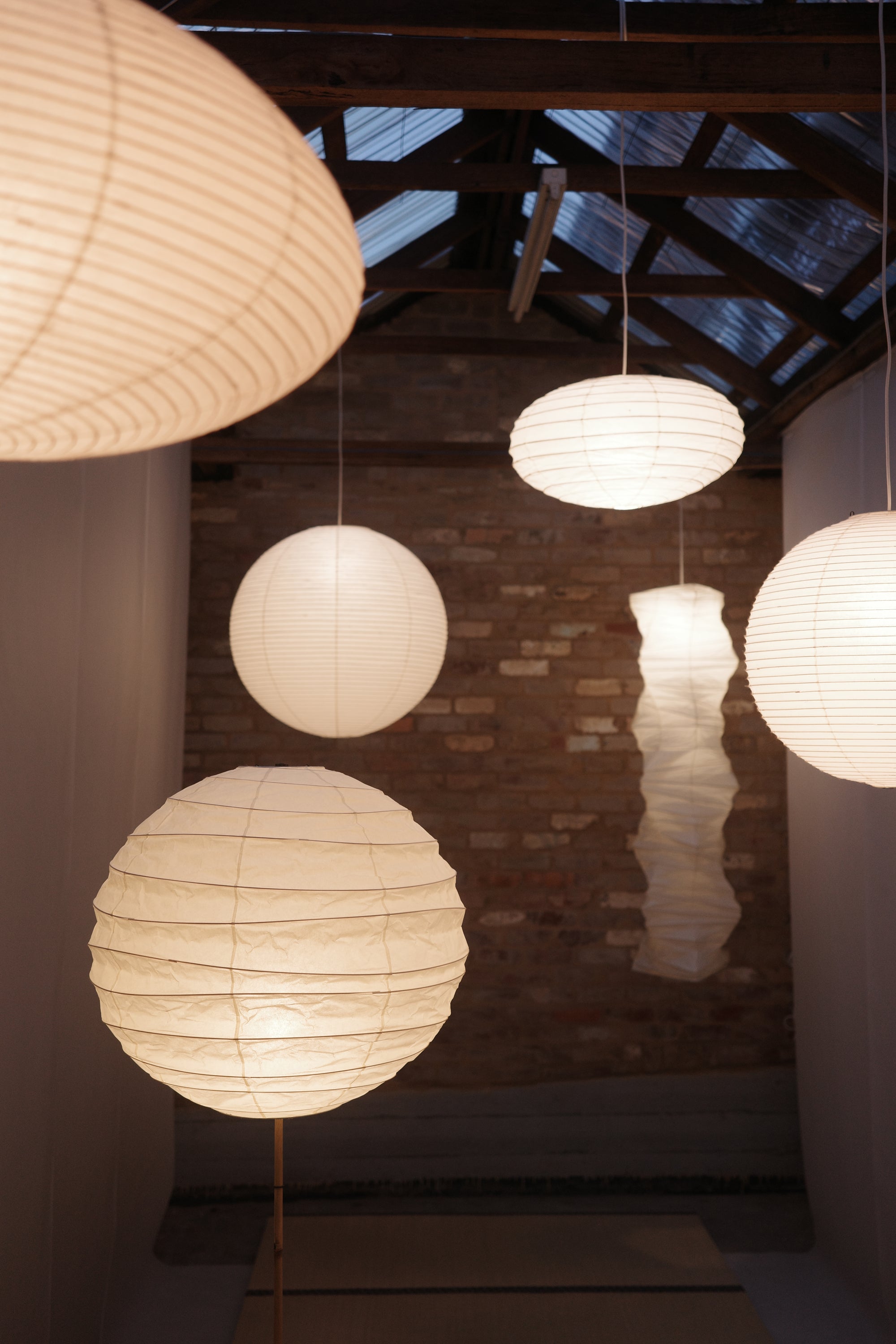 White spherical lamps hanging in a room with wooden walls and a textured ceiling.